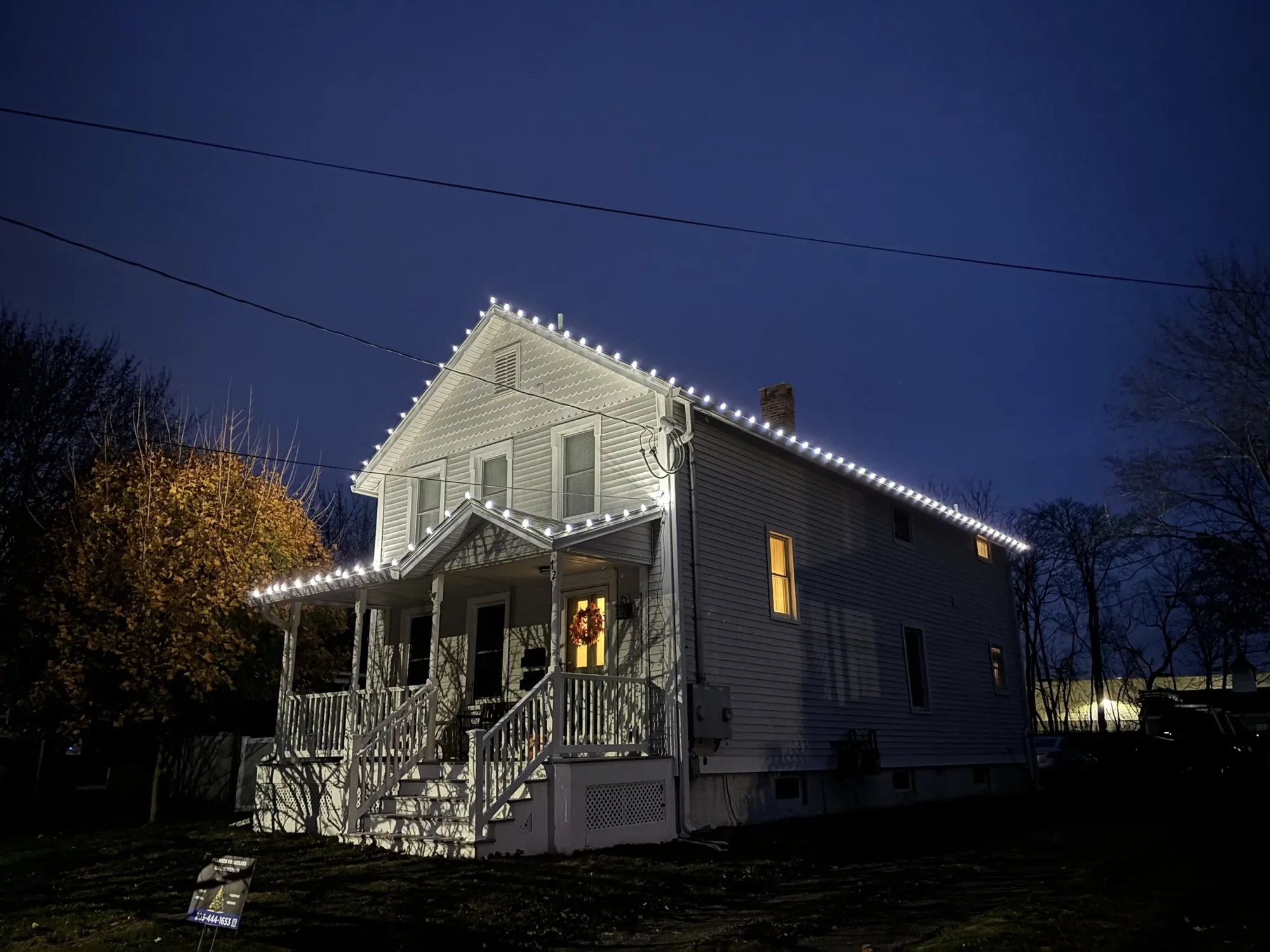 Farmhouse with lit gables and porch roof at dusk